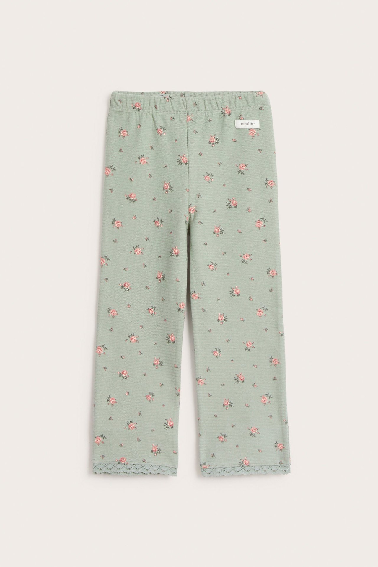 Vorderansicht von babygrünen ausgestellten Jersey-Leggings mit kleinem rosa Blumenmuster und Spitzenbesatz.