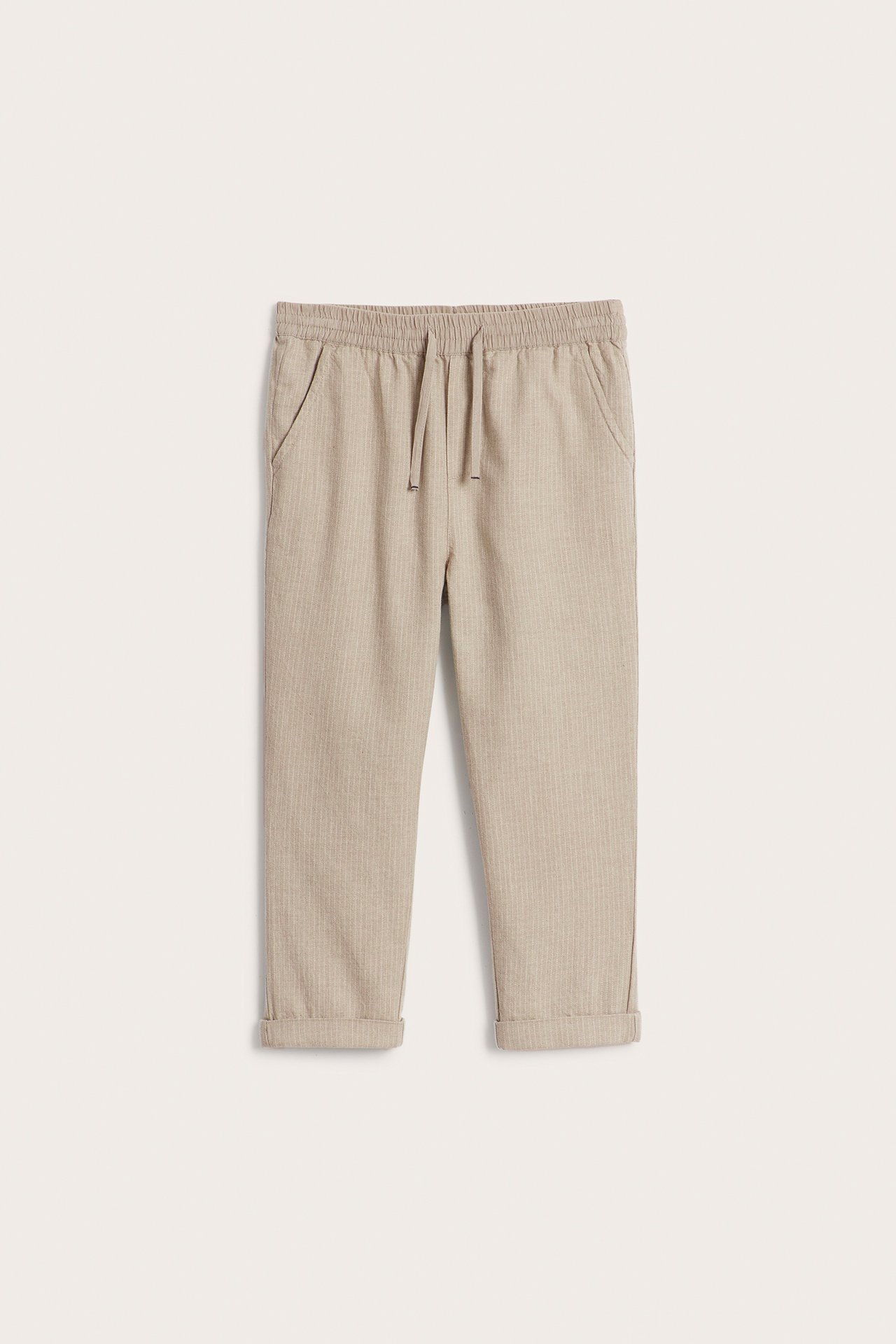 Front view: Kid's beige melange striped woven cotton trousers with an elastic drawstring waist and cuffed hems.