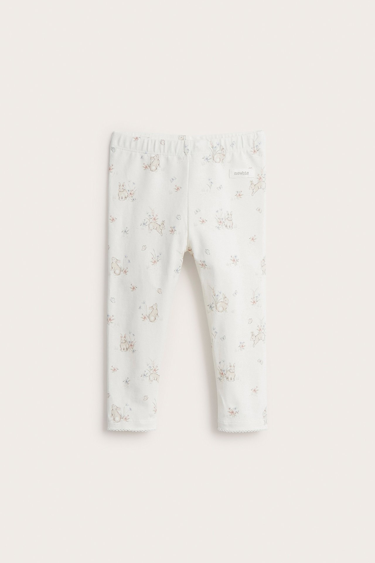 Front view of offwhite baby leggings with a rabbit print, elastic waist, and picot trim.