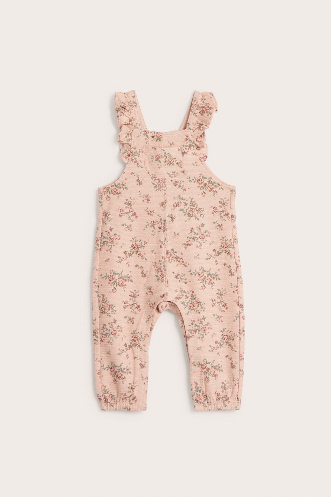 Vorderansicht eines rosa geblümten Baby-Overalls aus Strukturjersey mit Rüschenträgern und elastischen Knöcheln.