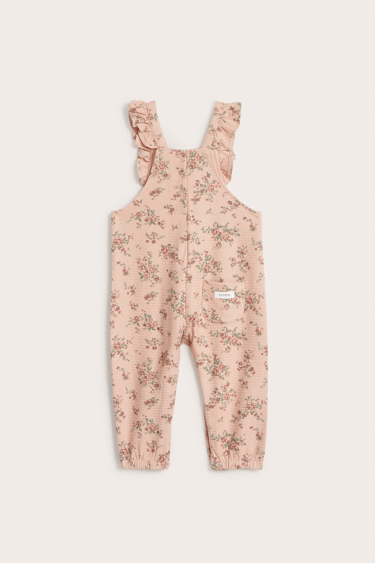 Vorderansicht rosa geblümter Baby-Latzhose aus Strukturjersey mit Rüschenträgern und Gummizug an den Knöcheln.