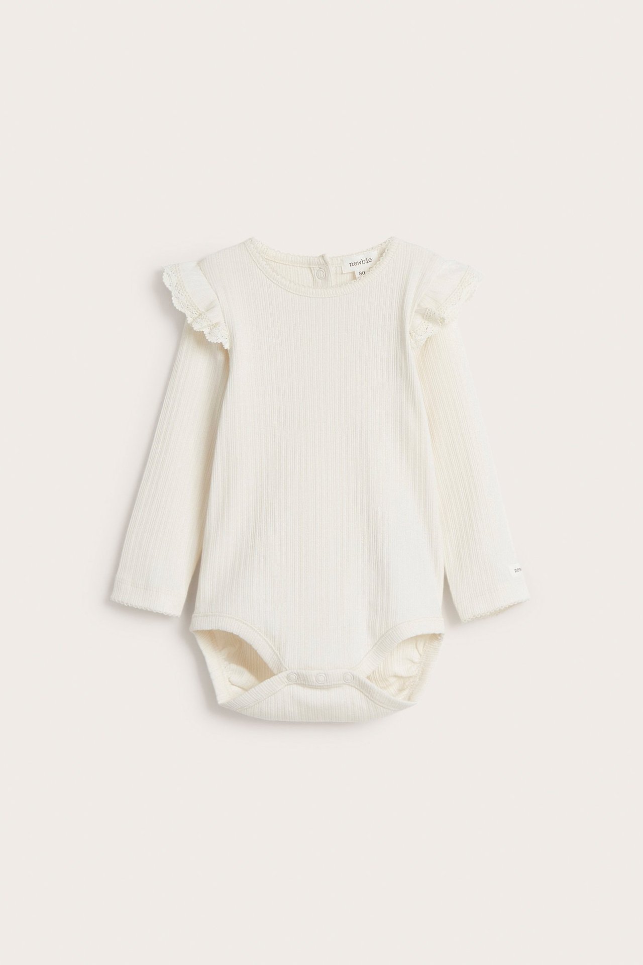 Vorderansicht: Off-white gerippter Baby-Body mit langen Ärmeln, Schulterrüschen und Druckknöpfen.