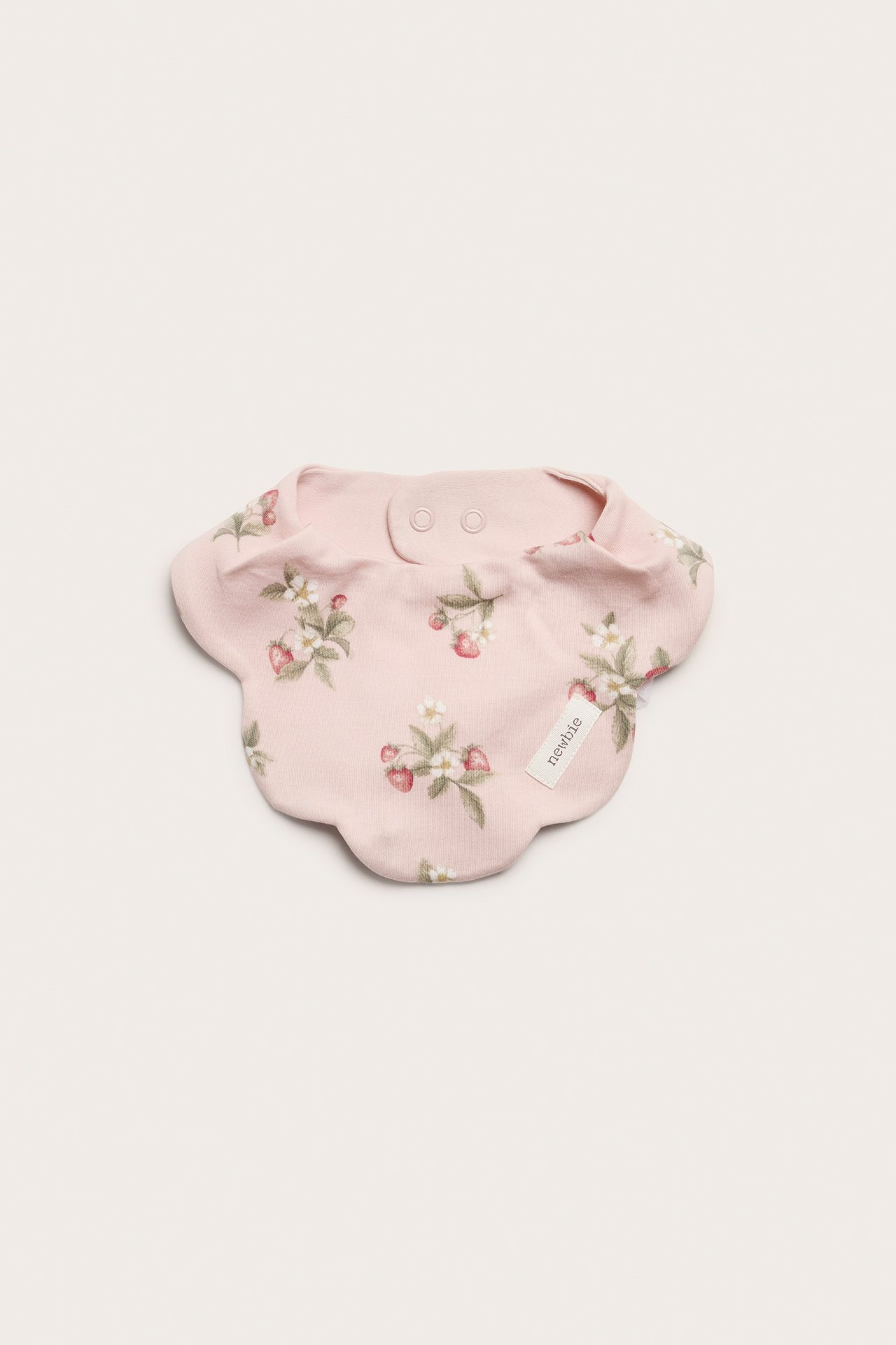Draufsicht: Hellrosa Baby-Lätzchen mit Erdbeer- und Blumenmuster, gewelltem Rand und Druckknöpfen.