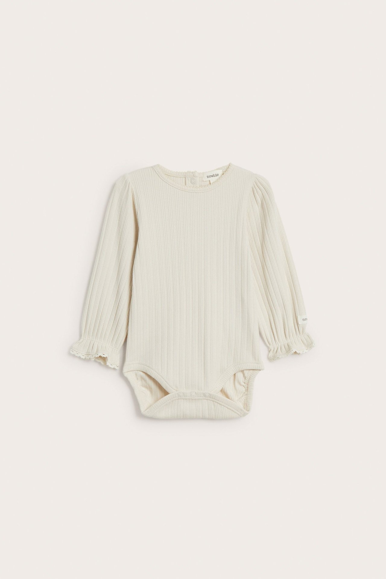Vorderansicht eines hellbeigen gerippten Baby-Bodys mit langen Ärmeln, Rüschenspitzenbündchen und Druckknöpfen.