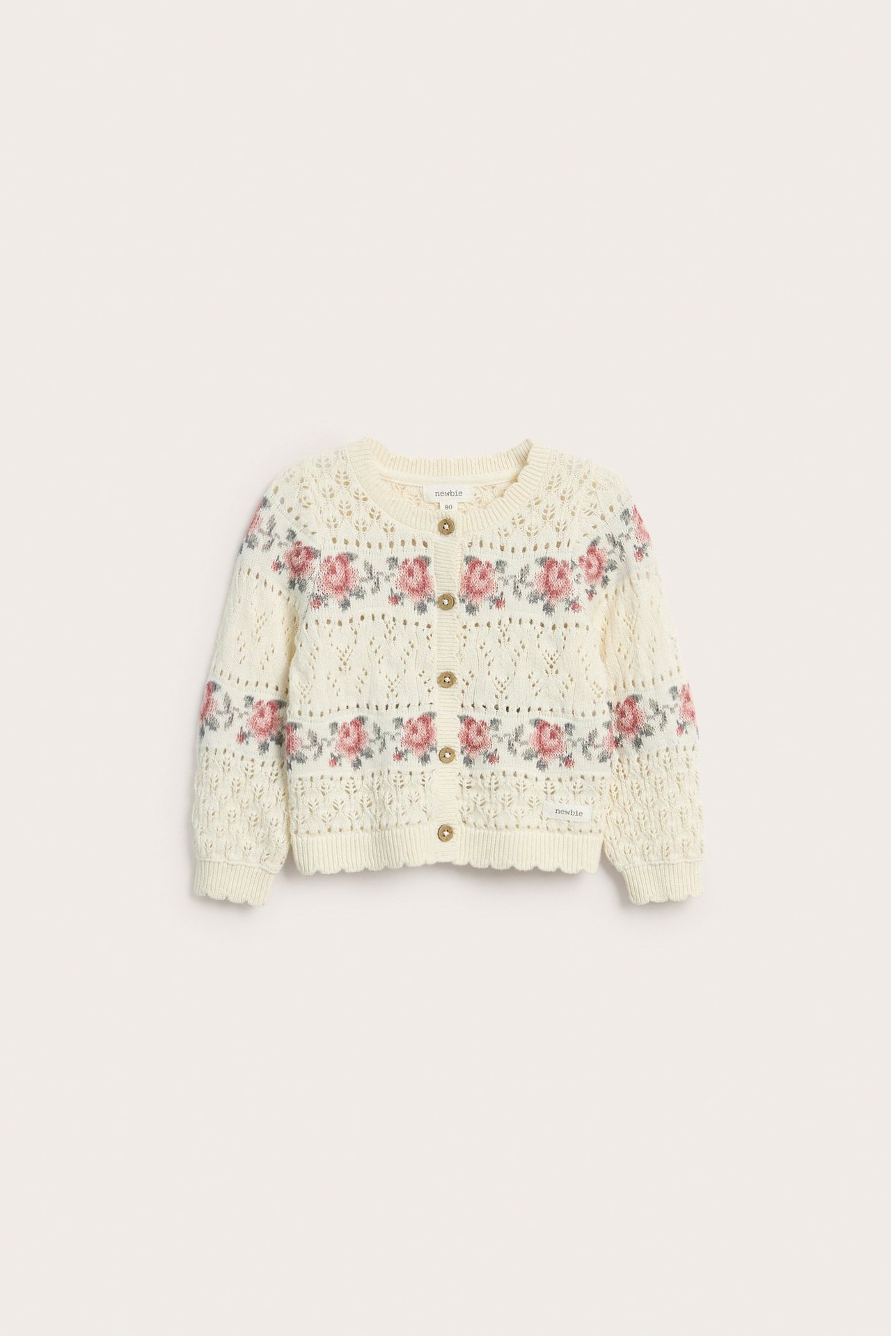 Vorderansicht einer cremefarbenen Baby-Jacquard-Strickjacke aus Baumwolle mit rosa Rosenmuster und Knöpfen.
