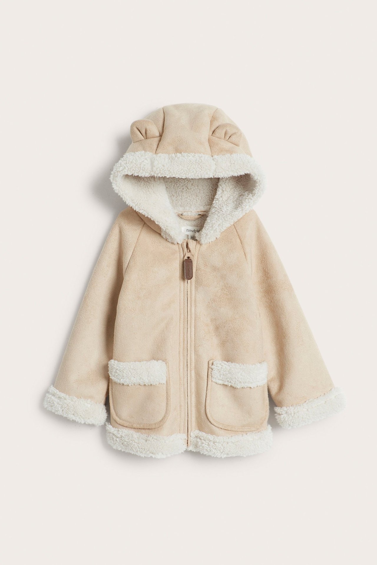 Vorderansicht: Beigefarbene Kinder-Shearlingjacke aus Faux-Wildleder mit Teddyfutter, Ohrenkapuze, Reißverschluss, Taschen.