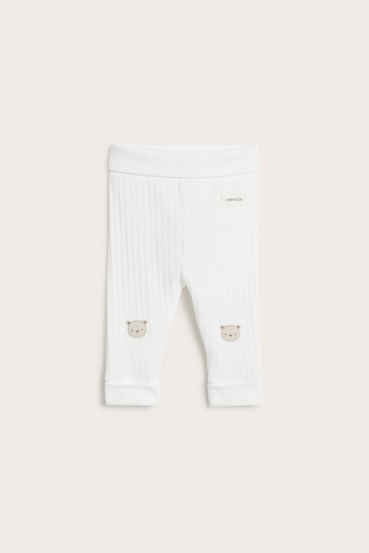 Front view of off-white ribbed jersey baby leggings with bear applications on the knees.
