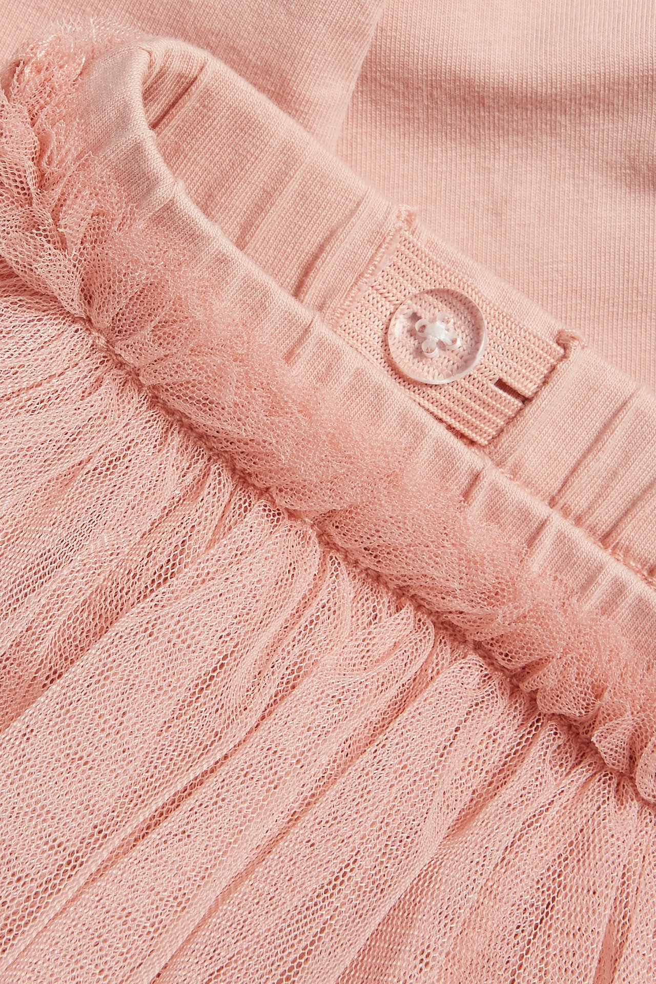 Nahaufnahme von rosa Baumwoll-Leggings mit angenähtem dreistufigem Tüllrock und verstellbarem Gummibund.