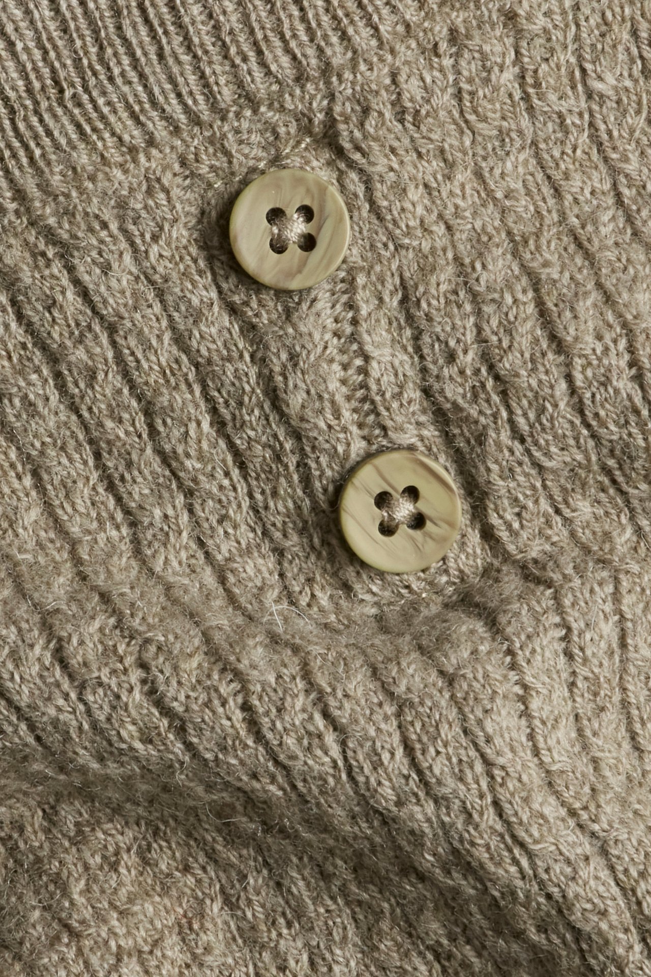 Close-up of beige melange wool-blend structured knit leggings with two decorative buttons.