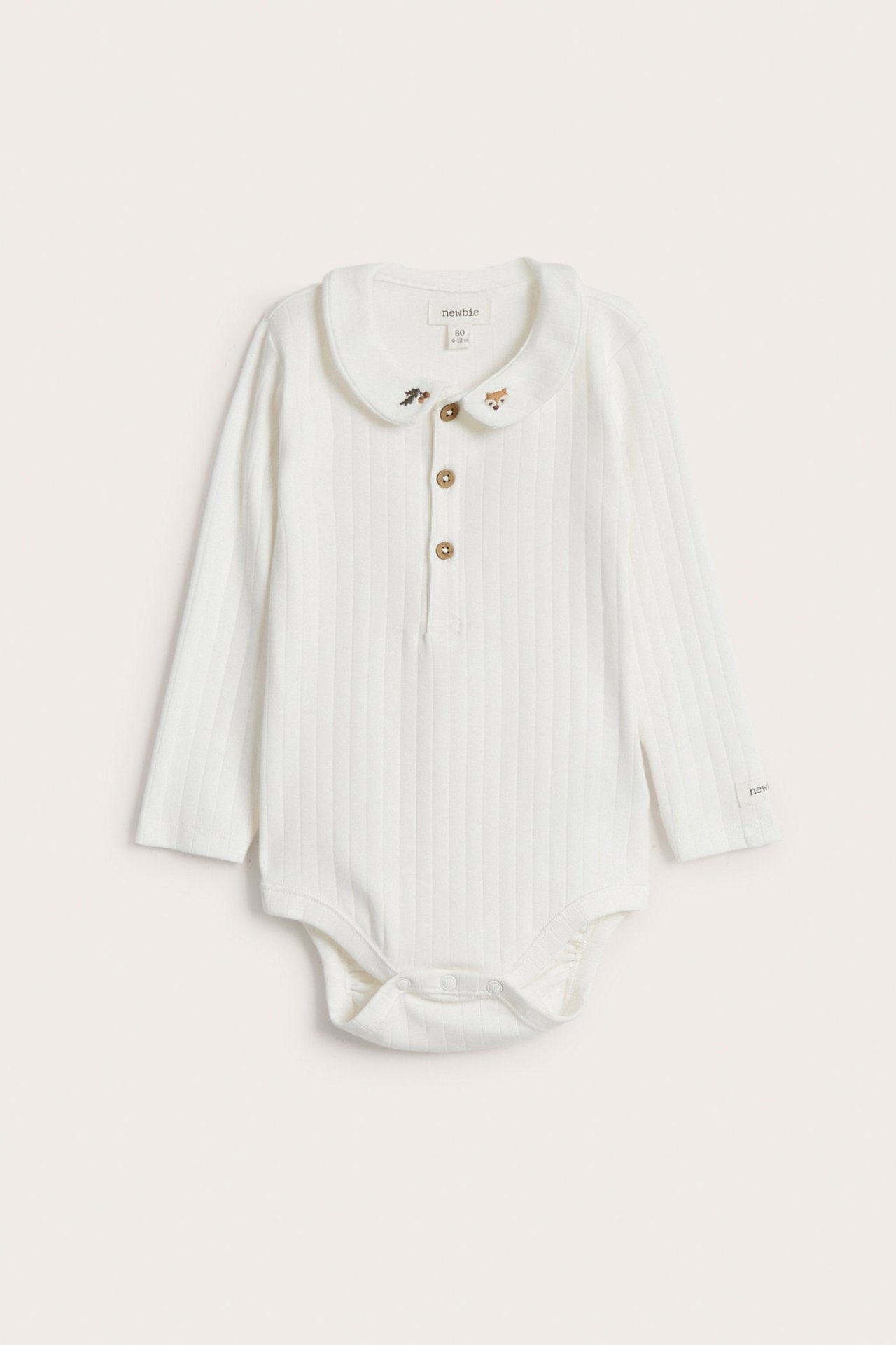 Vorderansicht: Off-white gerippter langärmeliger Baby-Body mit Kragen, Fuchsstickerei, Knöpfen vorne und Druckknöpfen im Schritt.