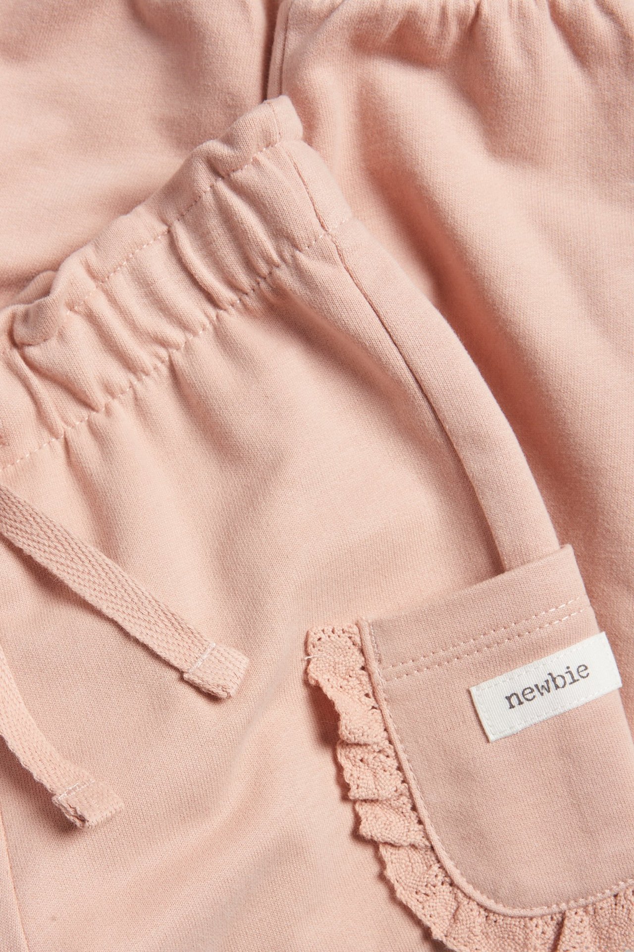 Nahaufnahme von rosa Baumwoll-Jogginghose mit Gummizug, Kordelzug und spitzenbesetzten Seitentaschen.