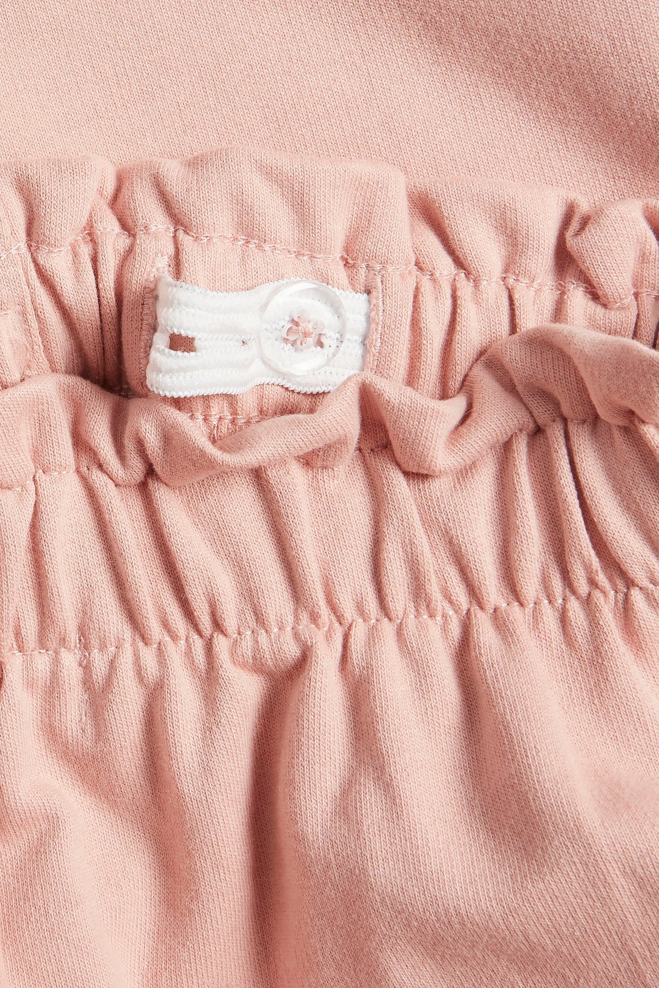 Nahaufnahme von rosa Baumwoll-Jogginghose mit verstellbarem Gummibund und weißem Knopf.