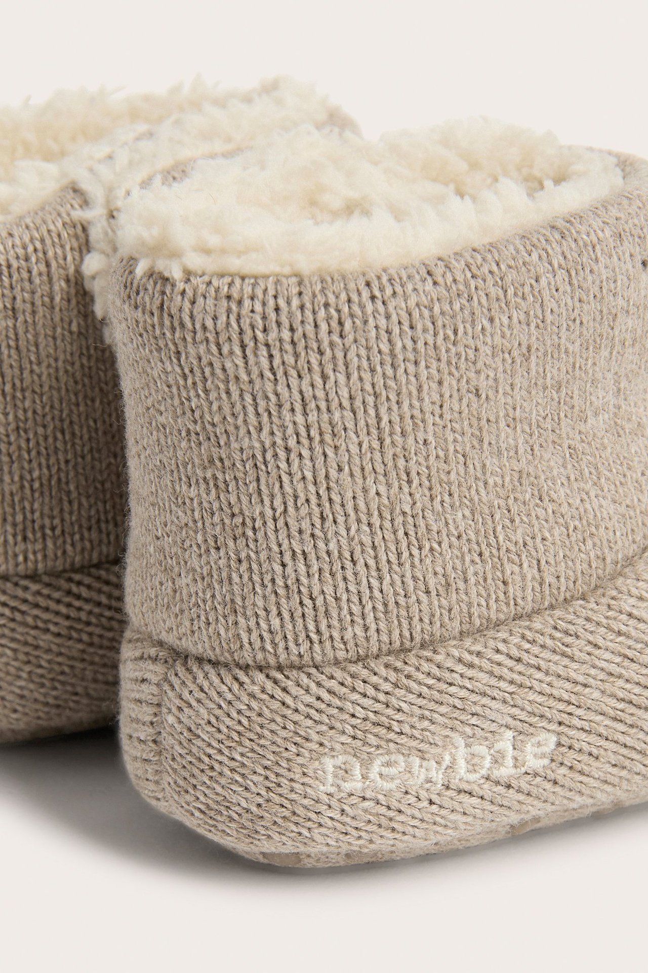 Close-up of light brown knitted baby booties with a cream fluffy pile lining.