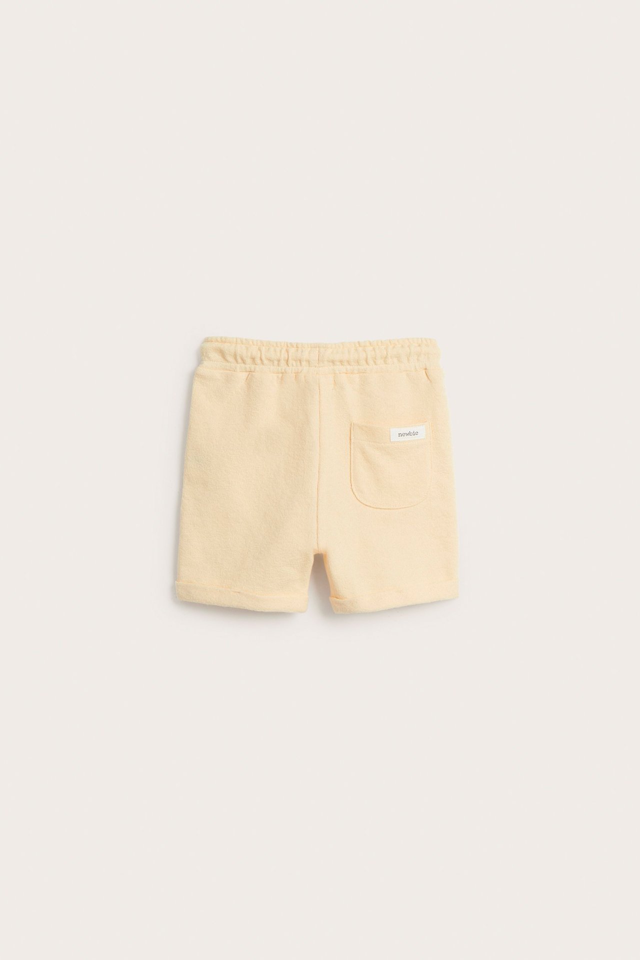 Back view of light yellow cotton shorts with elastic waist, back pocket, and rolled-up hems.