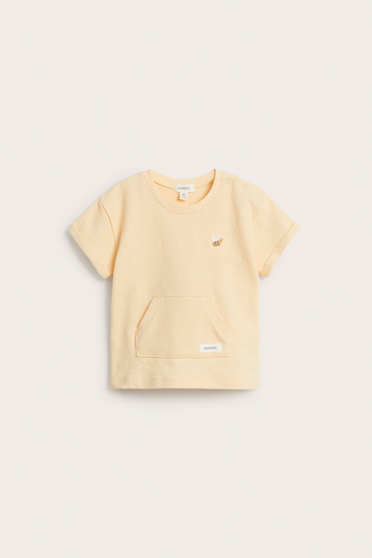 Front view: baby's yellow cotton short-sleeved t-shirt with bee embroidery, shoulder snaps, and front pocket.