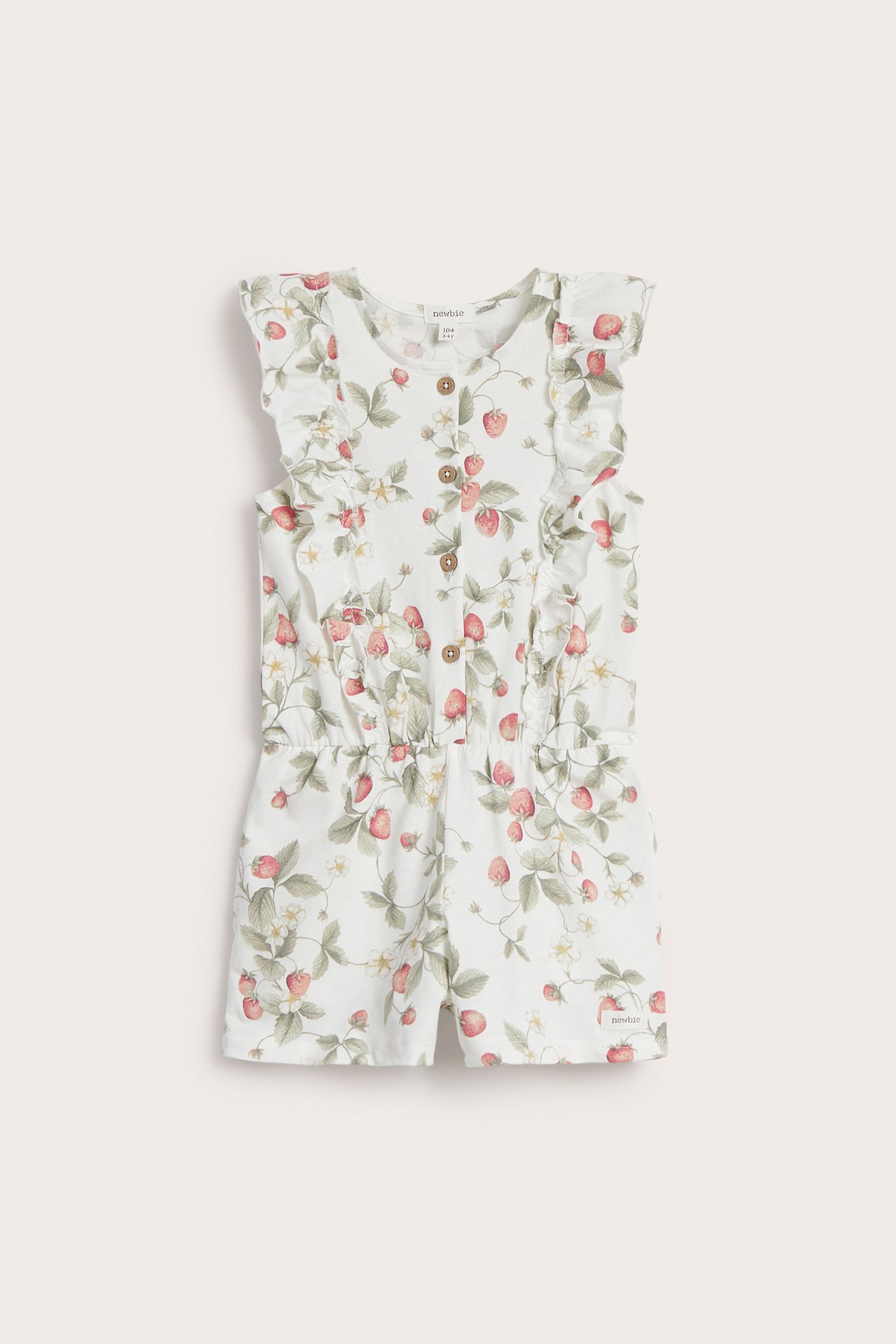 Front view: Kid's off-white cotton jersey jumpsuit with strawberry print, ruffles, short legs, and front buttons.