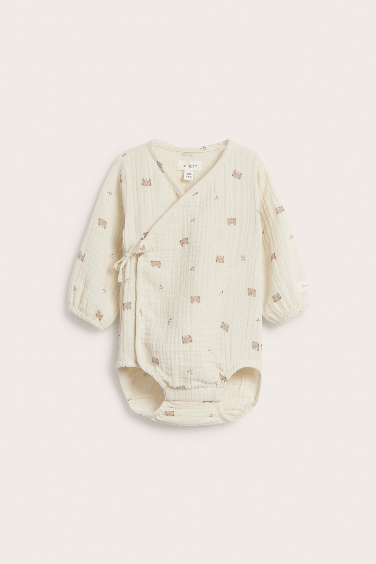 Front view of a baby's light beige cotton muslin wrap bodysuit with long sleeves and a bear print.