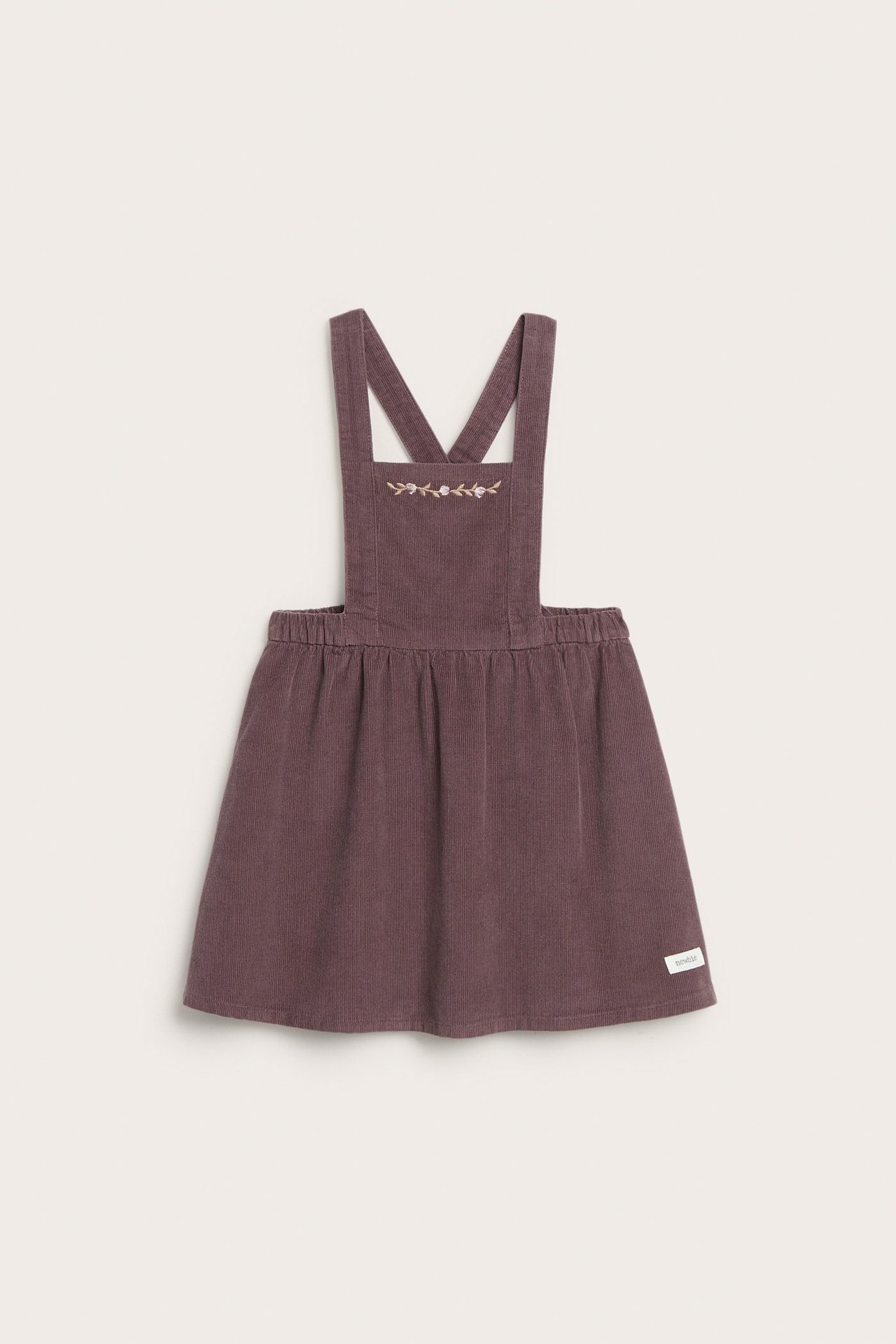 Front view of a lilac corduroy pinafore dress with floral embroidery on the bib and an elasticated waist.