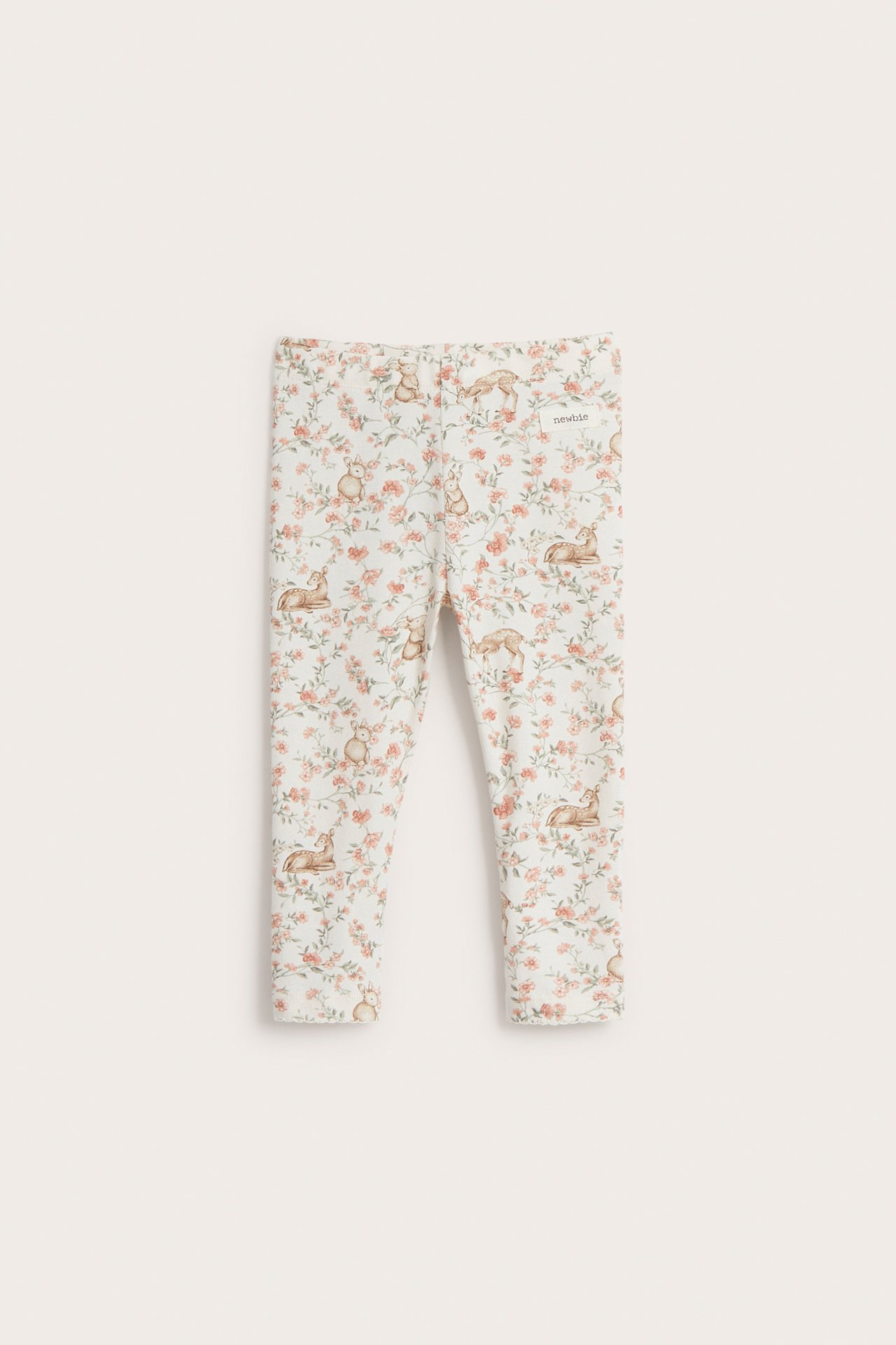 Front view of kid's off-white cotton leggings with a floral and animal pattern.