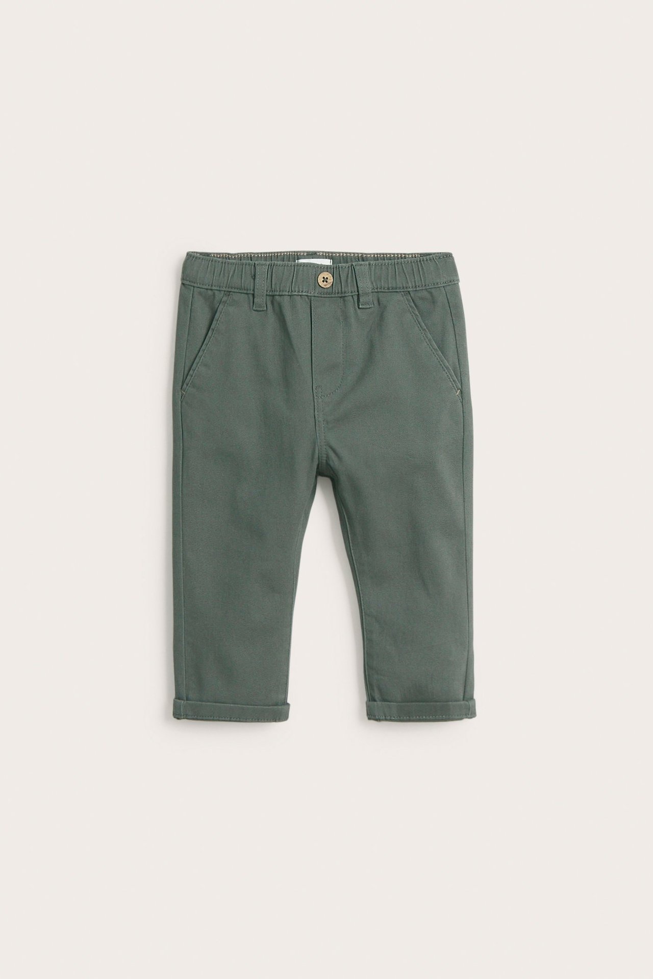 Front view of kid's dark green woven pants with elastic waist, button, side pockets, and cuffed hems.