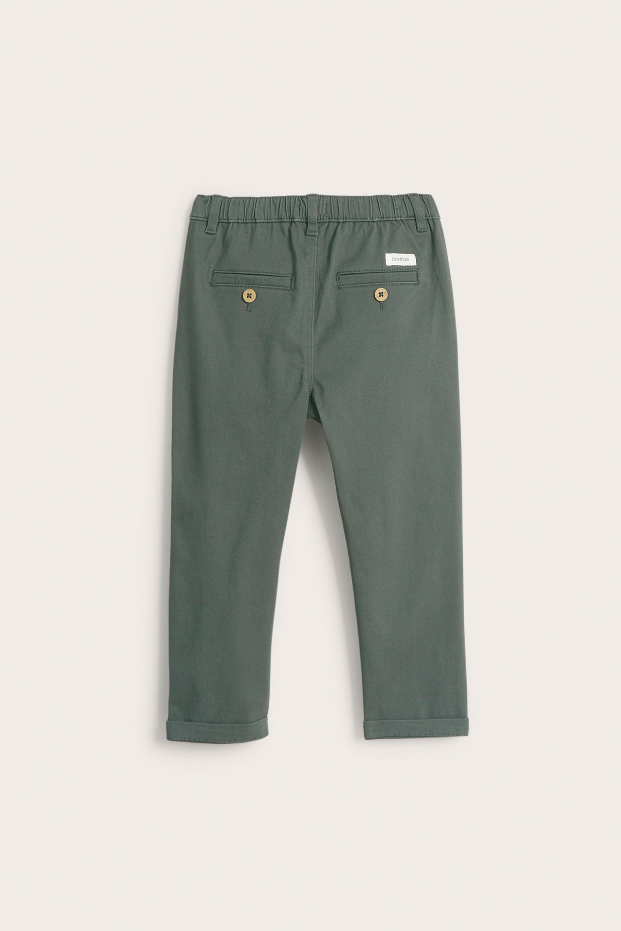 Back view of kid's dark green woven pants with an elastic waist, decorative back pockets, and cuffed hems.