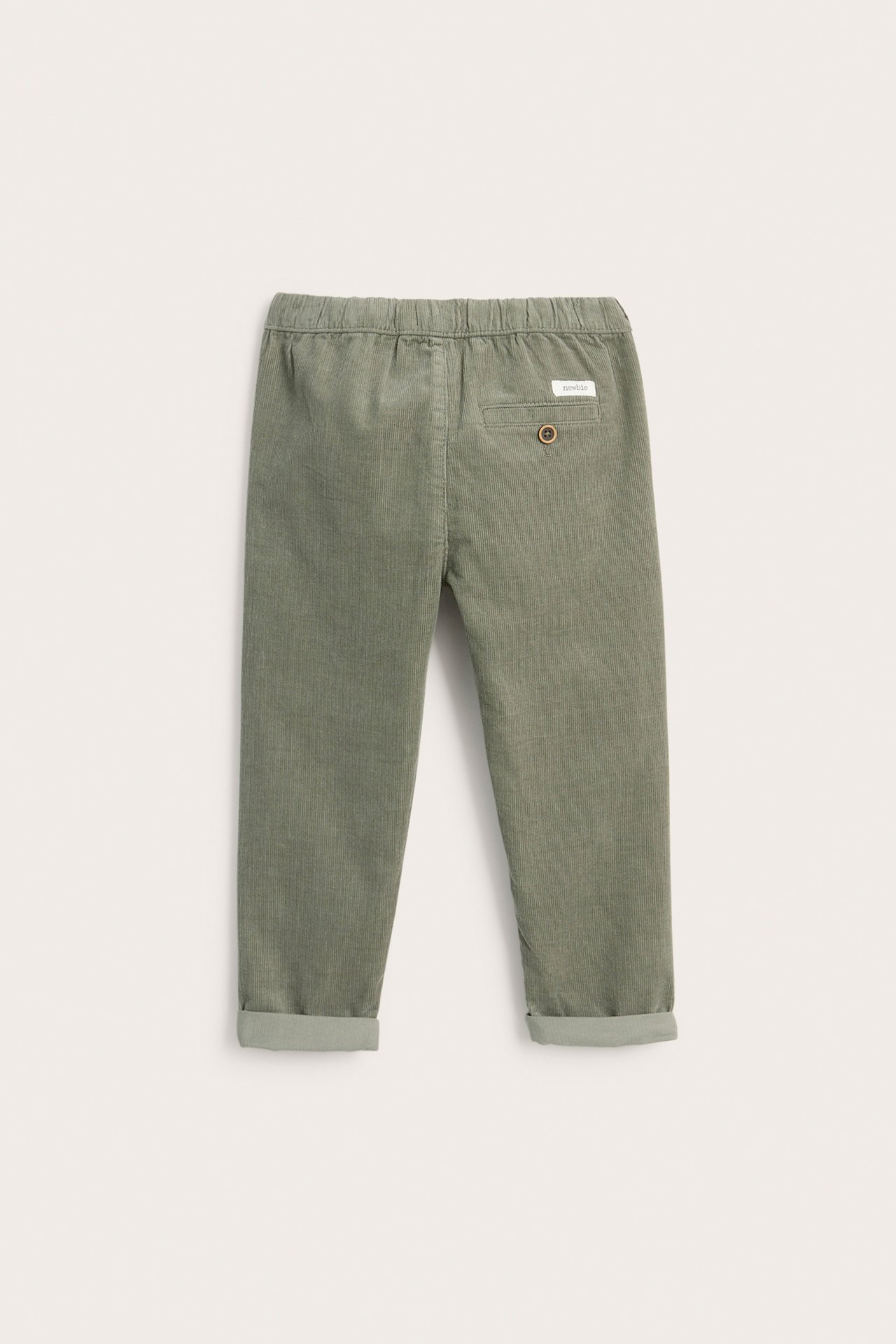 Back view of dark green kid's corduroy trousers with an elasticated waist and a back pocket with button.
