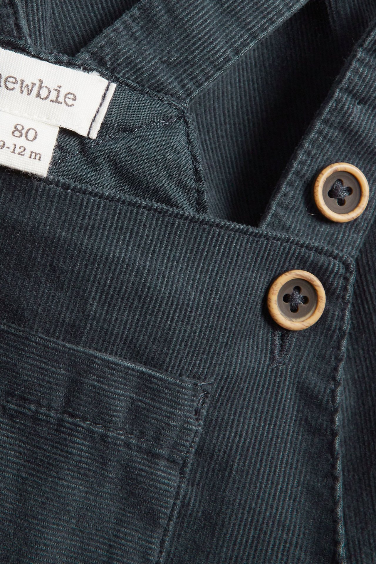 Dark blue Manchester suspender pants with adjustable straps, chest pocket, and side pockets.