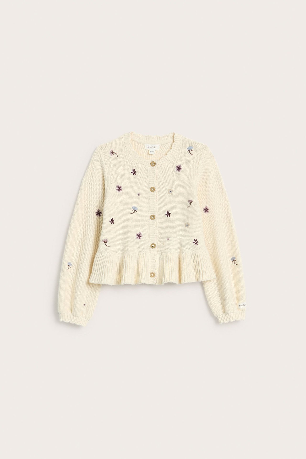 Vorderansicht einer hellbeigen Kinder-Strickjacke aus Baumwolle mit Blumenstickerei, gerippten Kanten und Rüschensaum.