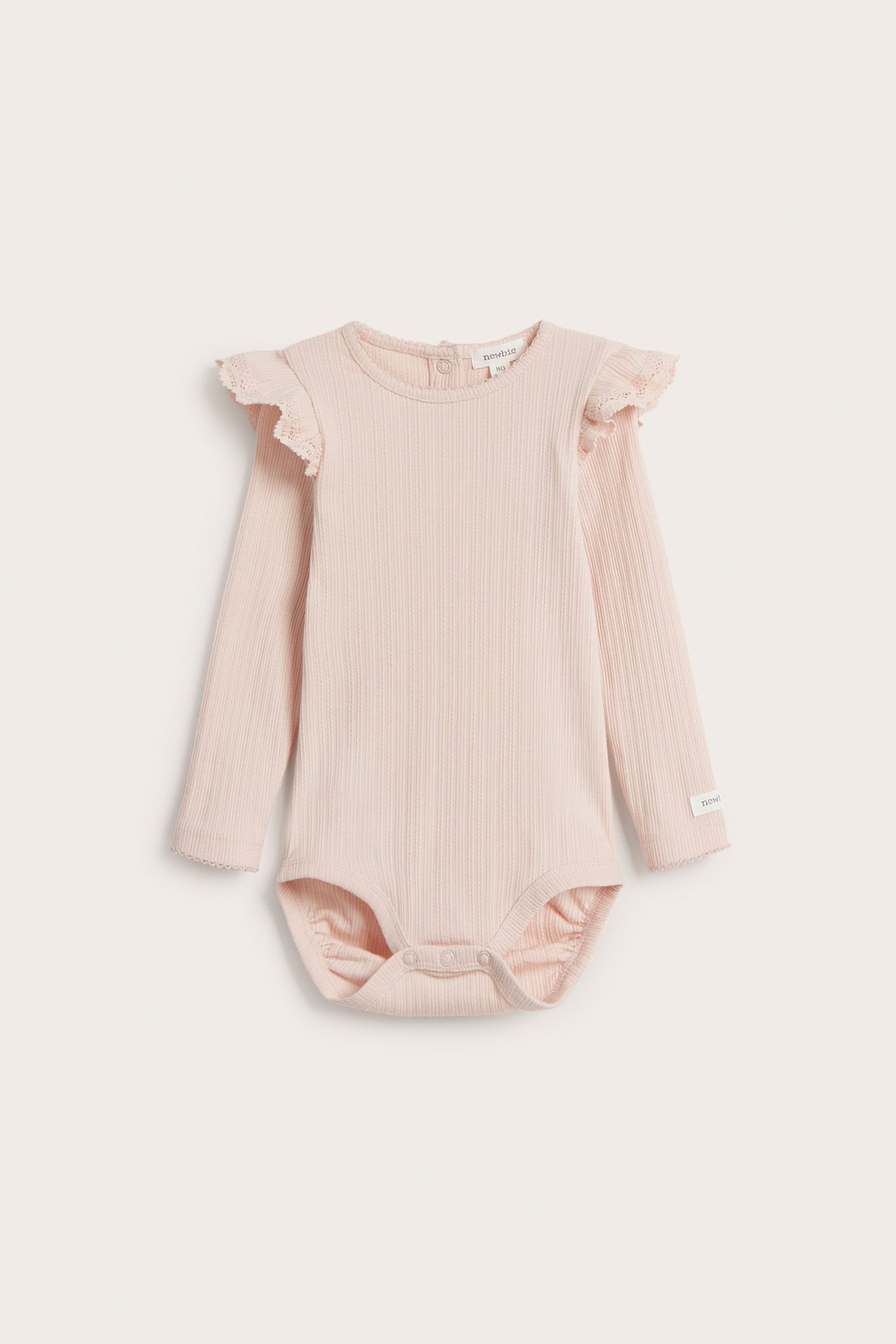 Front view of a light pink ribbed baby bodysuit with long sleeves, shoulder ruffles, and snap buttons.