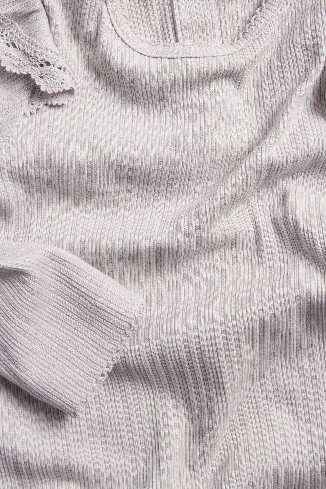 Close-up of a light lilac ribbed bodysuit with a lace-edged ruffle on the shoulder.