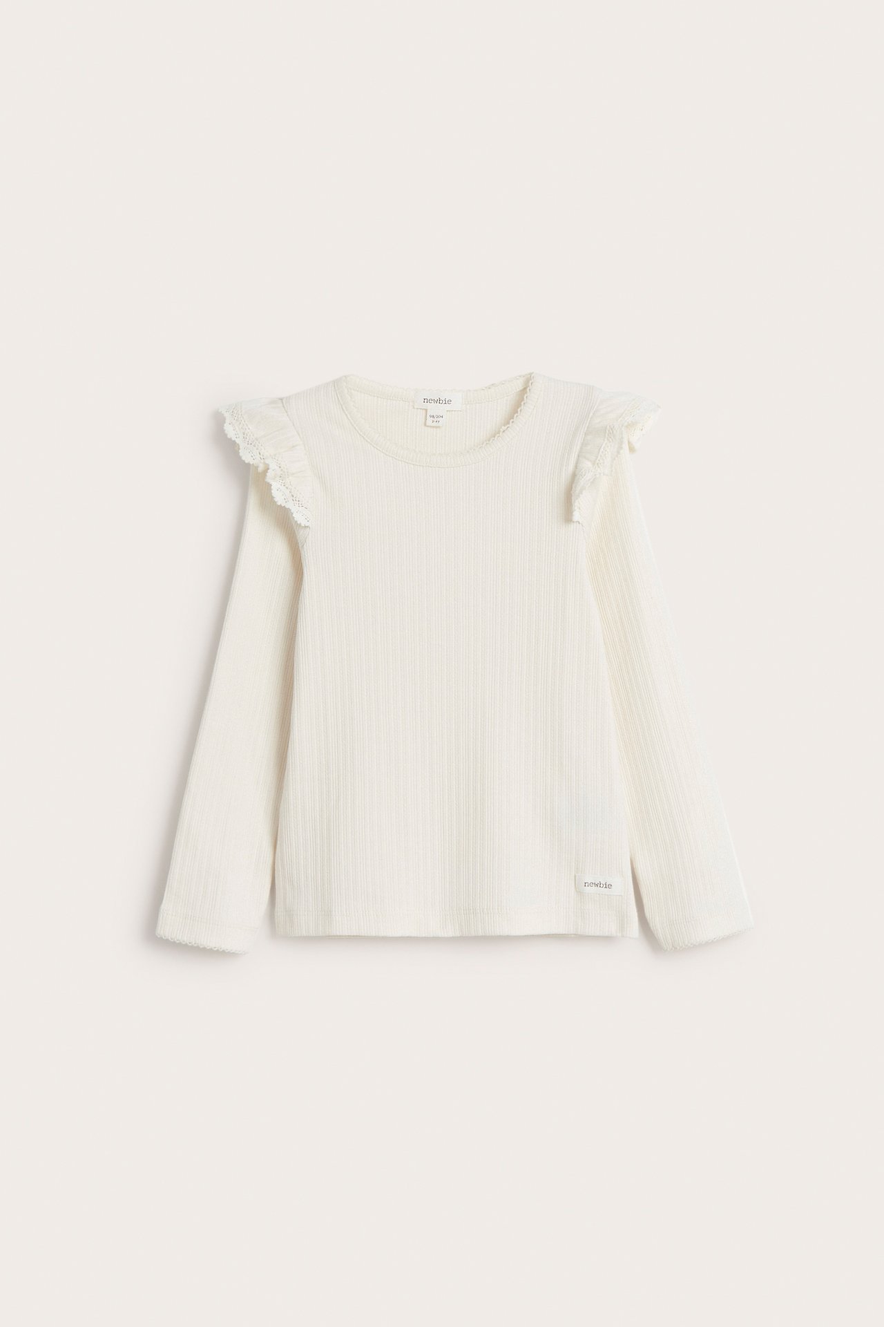 Front view of an offwhite ribbed long-sleeved kid's top with lace-trimmed ruffles on the shoulders.