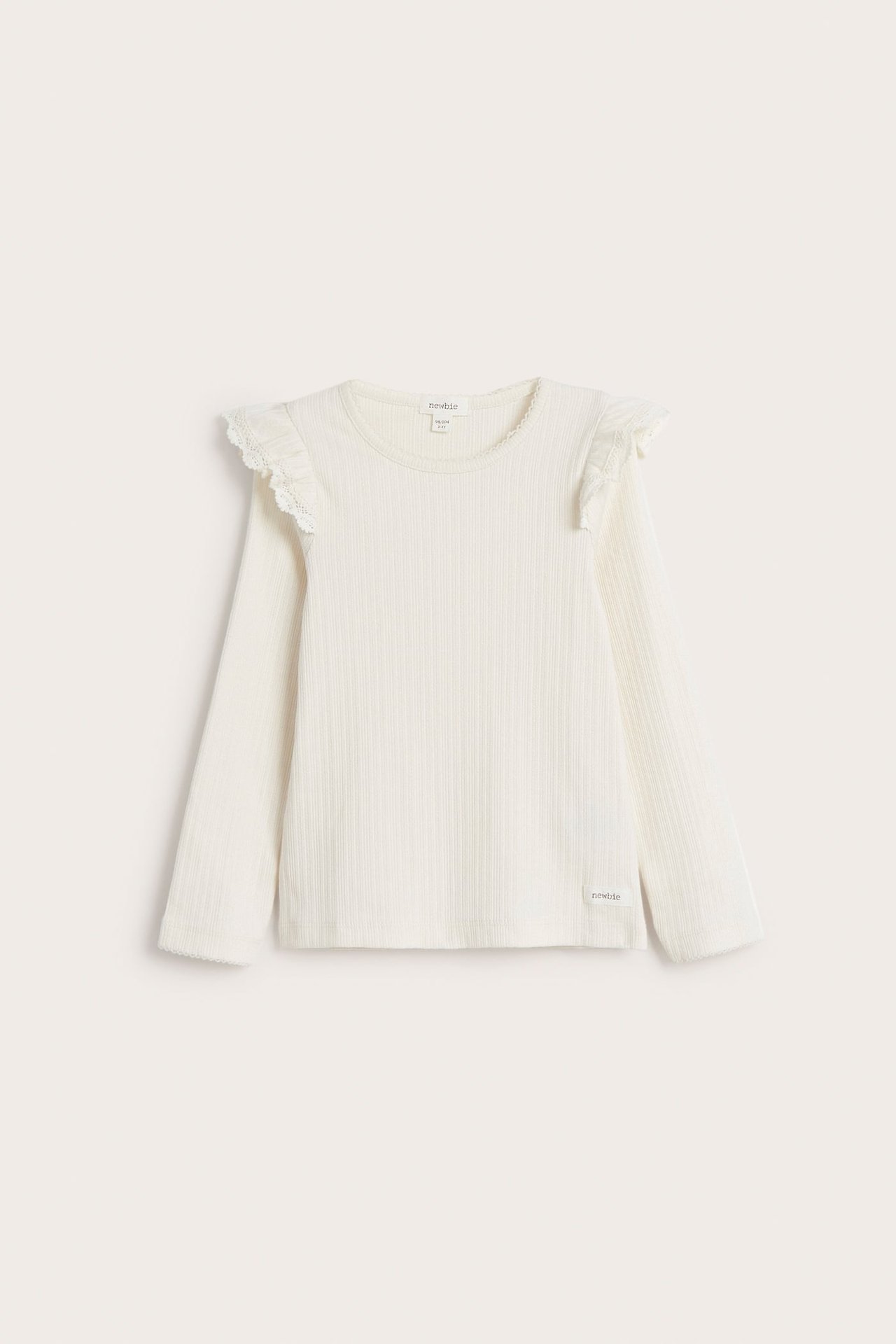 Vorderansicht eines cremeweißen gerippten Langarmshirts für Kinder mit Rüschen und Spitzenbesatz an den Schultern.