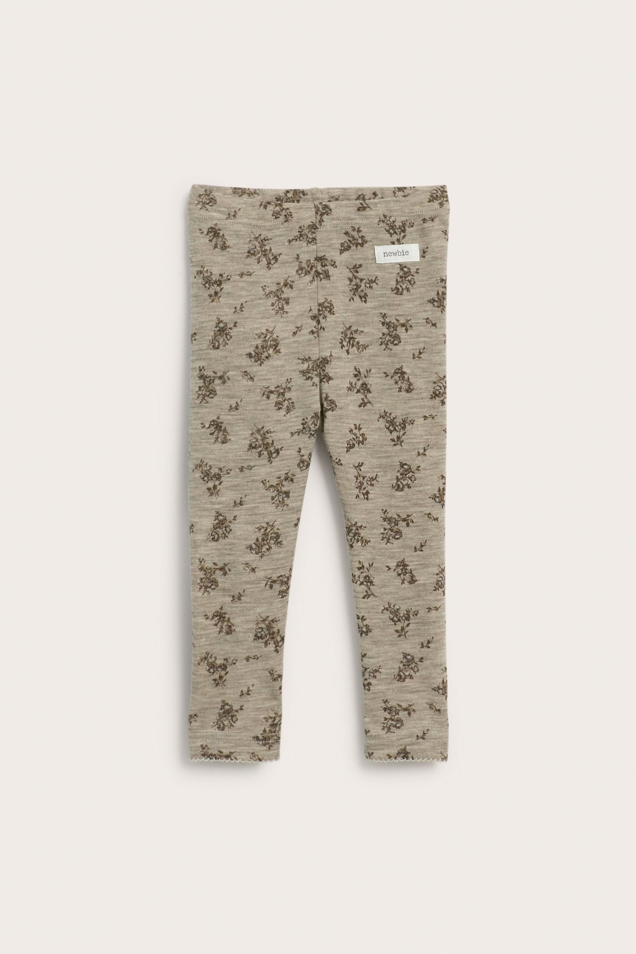 Front view of baby's beige melange merino wool leggings with a dark floral pattern and picot trim.