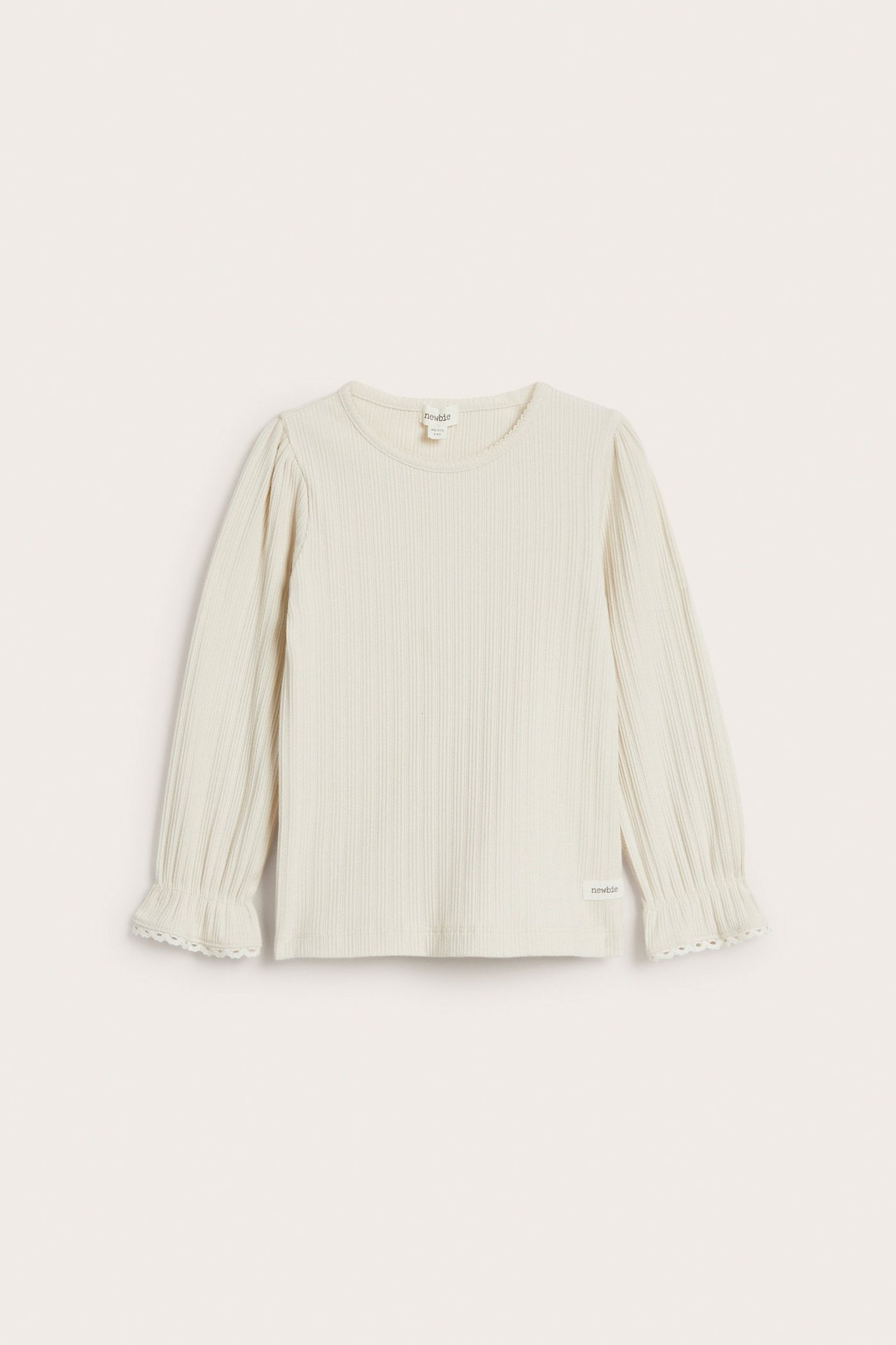 Vorderansicht: Helles beiges geripptes Langarmshirt für Kinder mit Puffärmeln, Picot-Ausschnitt und Rüschenmanschetten mit Spitze.