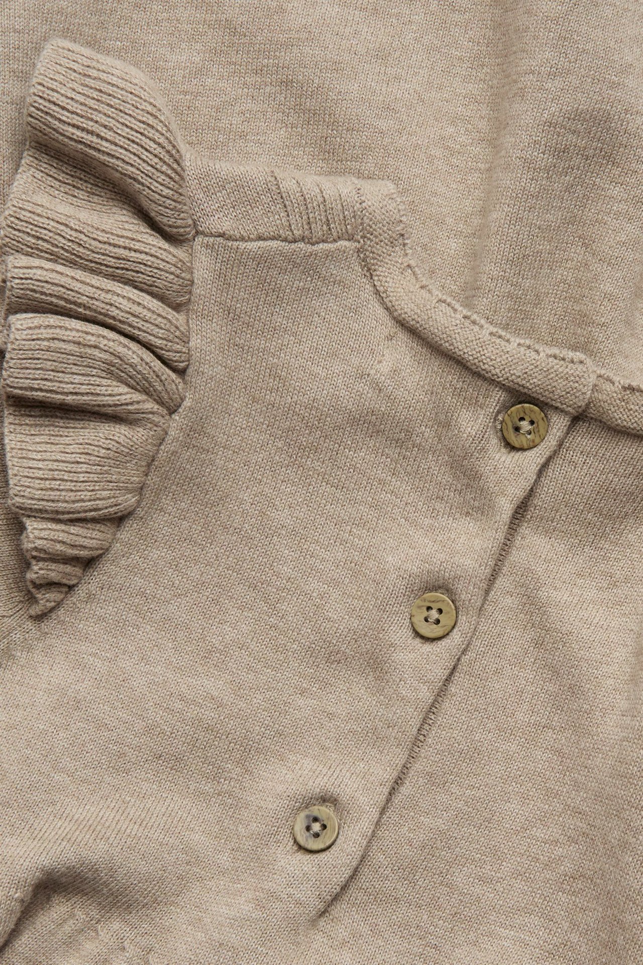 Close-up of a brown melange fine-knit cotton dress with ruffles on the shoulder and three small buttons.