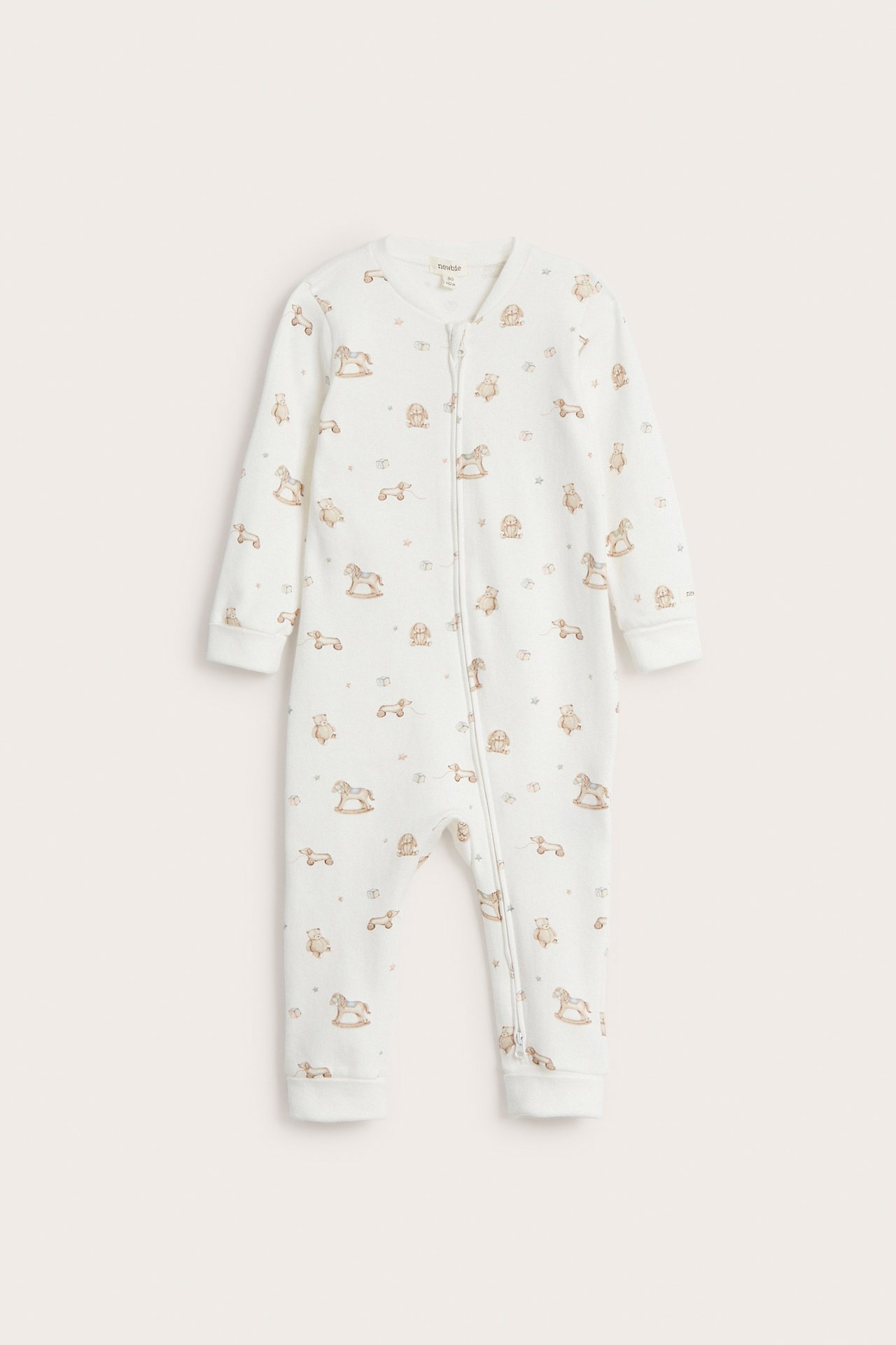 Front view of an off-white cotton baby romper with a toy pattern and a two-way zip.