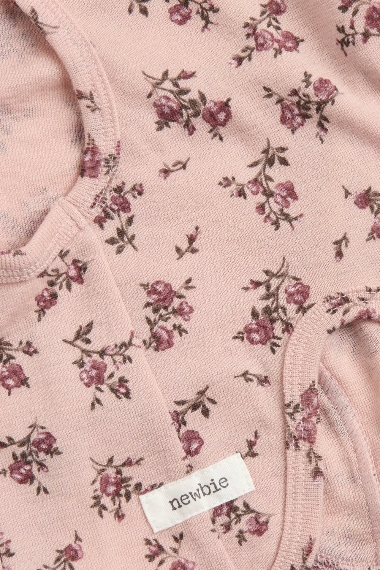 Nahaufnahme einer rosa geblümten Woll-Balaclava mit 'newbie' Etikett und sichtbaren Nähten.