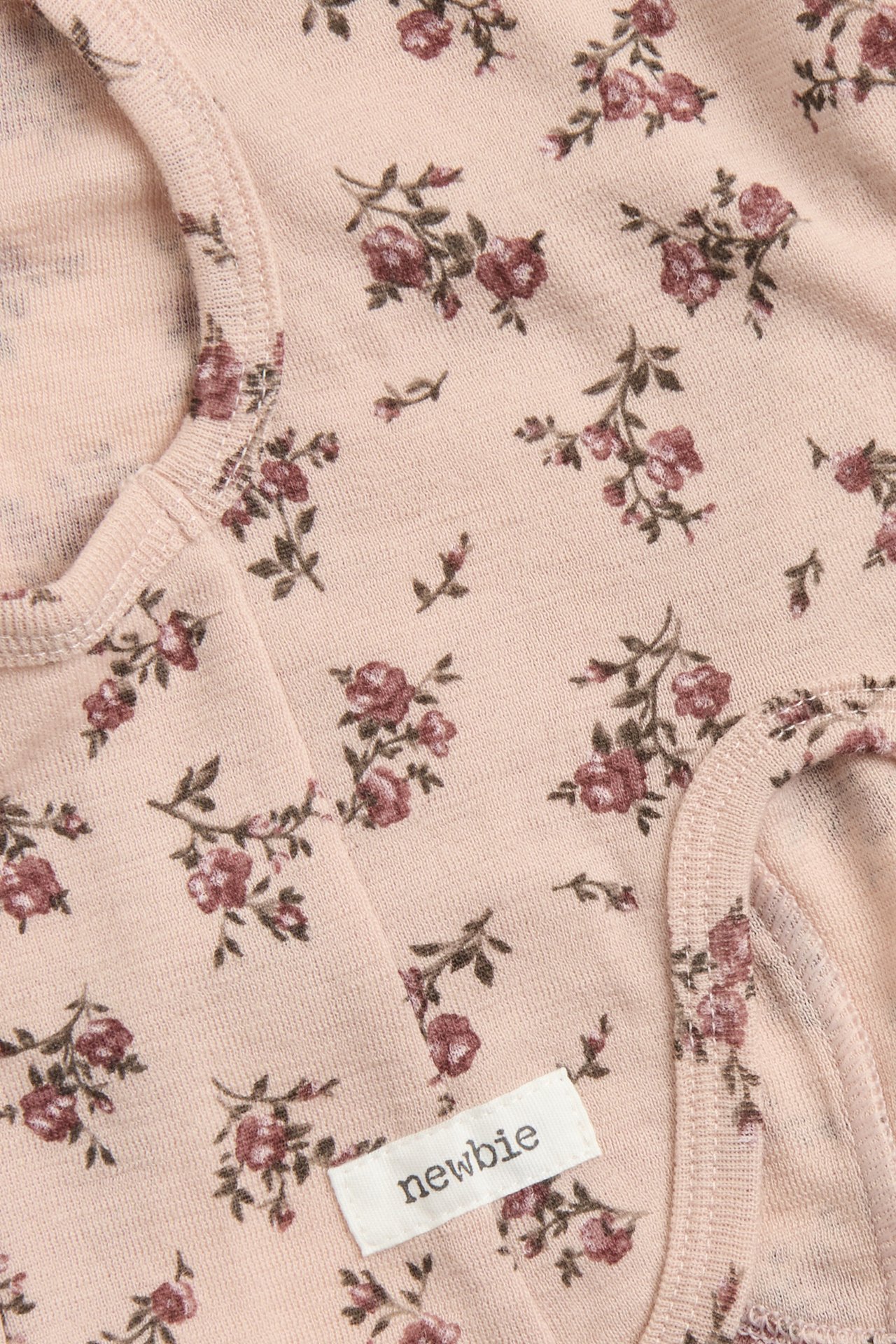 Close-up of a pink wool floral balaclava with a white 'newbie' brand label.