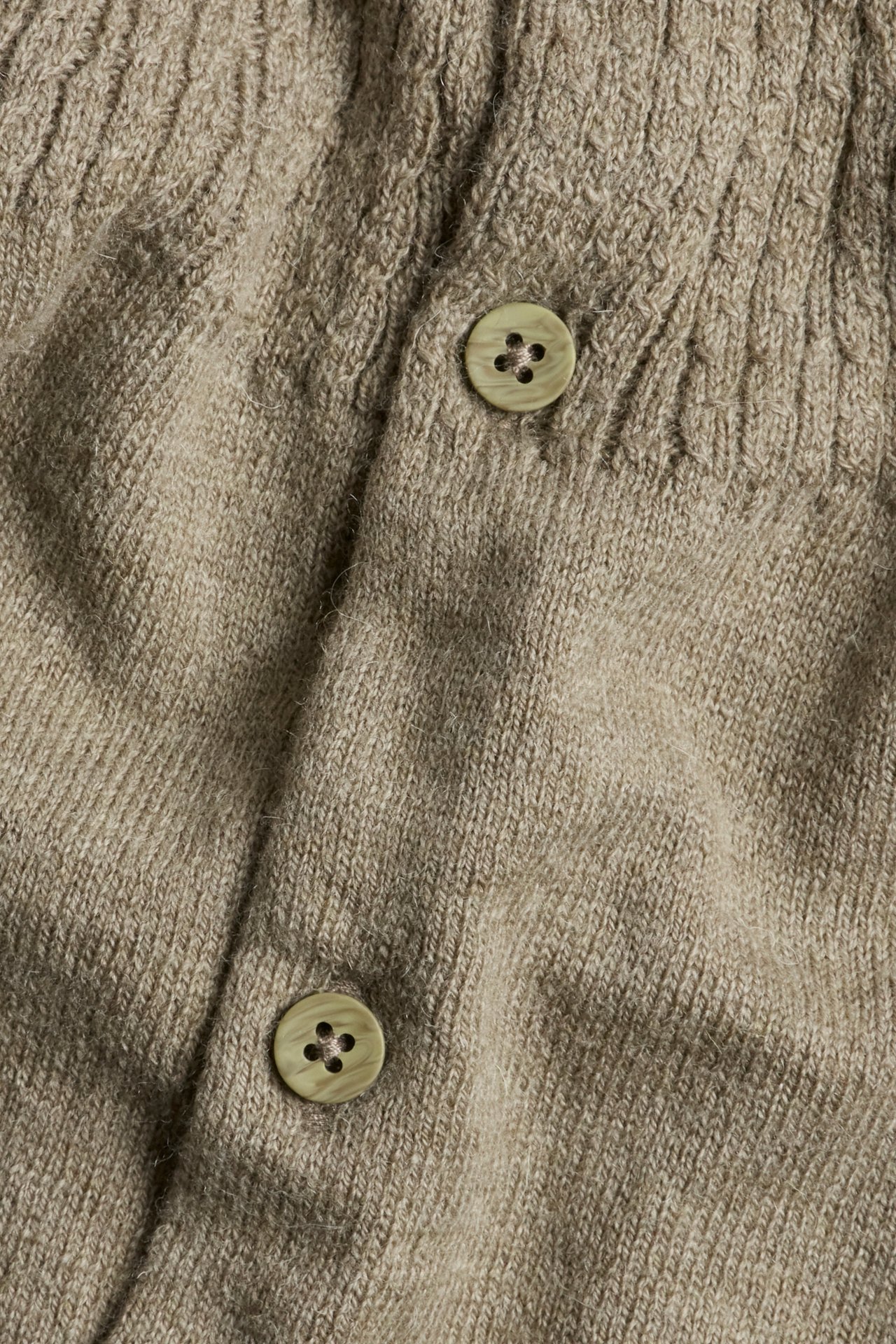 Nahaufnahme einer braunmelierten Strickjacke aus Wollmischung mit Zopfmuster und hellgrünen Knöpfen.