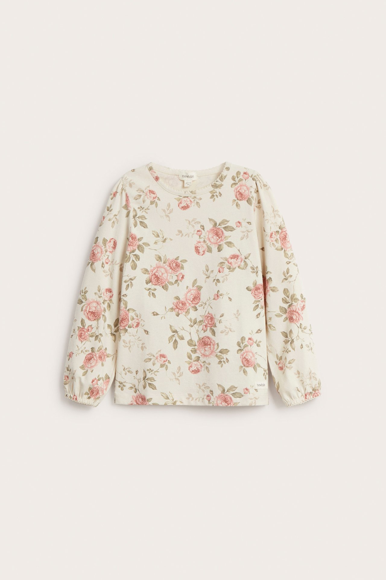Front view of a light beige cotton top with pink floral print, puff sleeves, and picot trim.