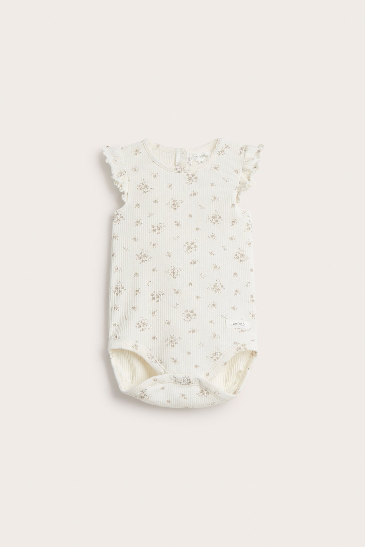 Front view of an off-white ribbed baby bodysuit with a floral pattern and ruffle sleeves.