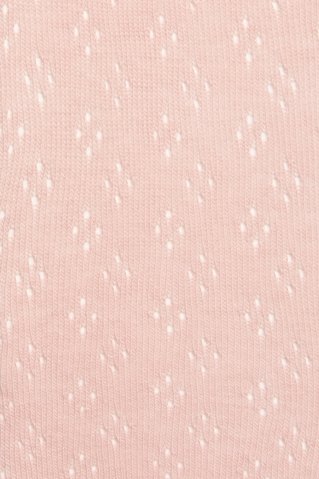Close-up of light pink tights with a delicate hole pattern.