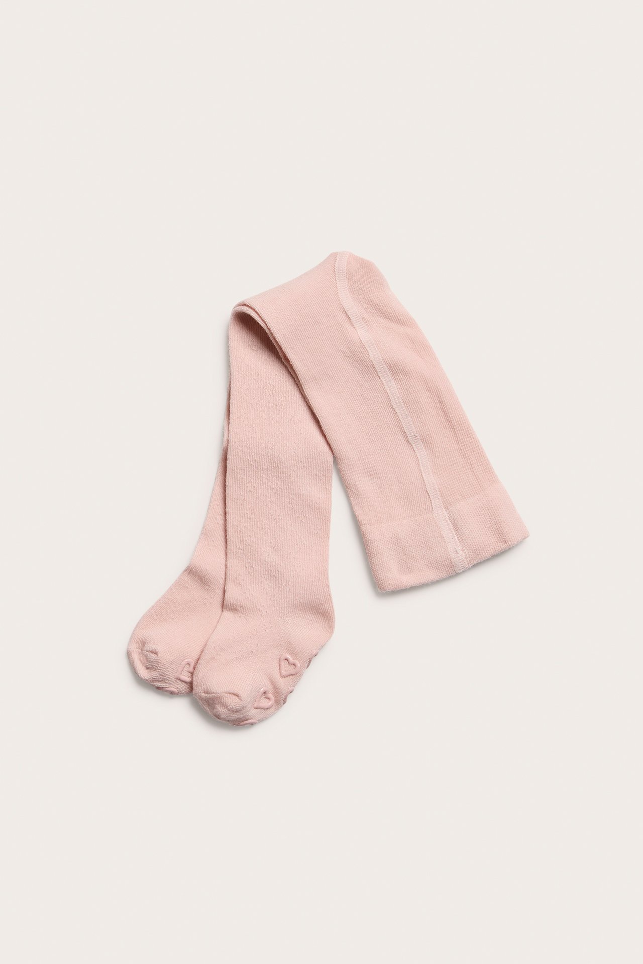 Top-down view of light pink baby tights with anti-slip heart details on the soles.