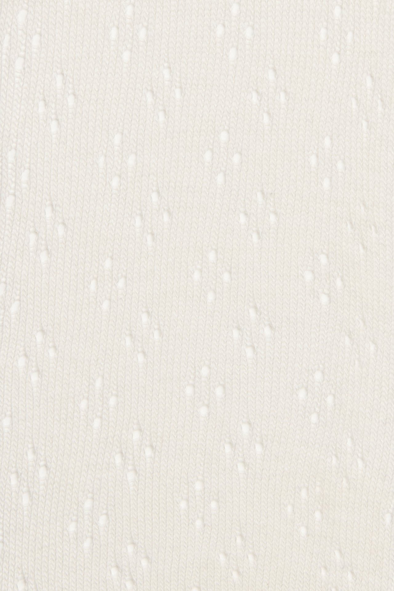 Close-up of off-white tights with a delicate hole pattern.