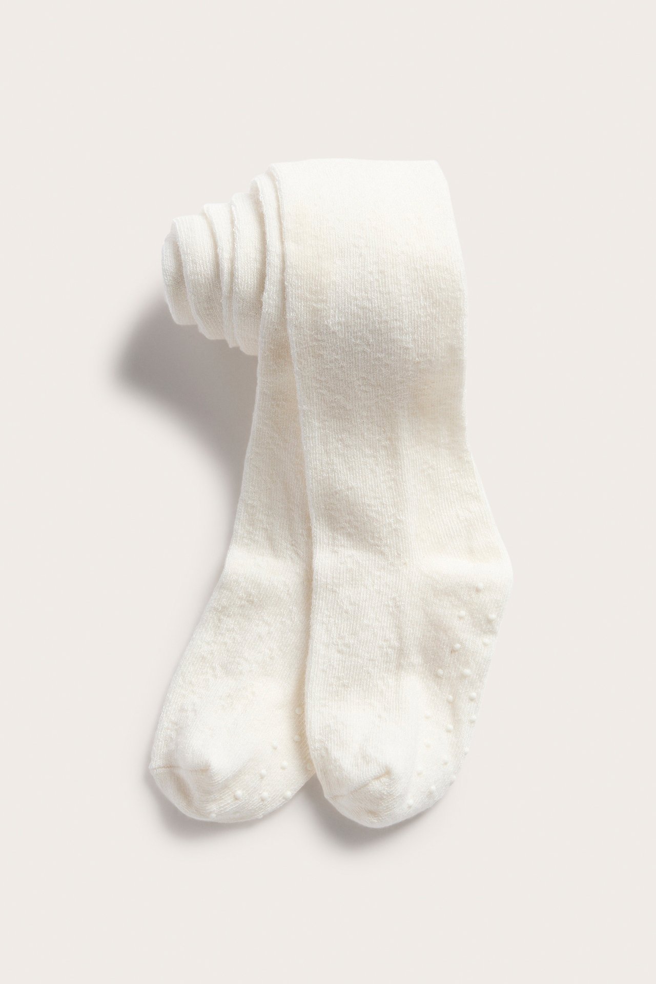 Vorderansicht: Cremefarbene Baby-Strumpfhose mit Anti-Rutsch-Sohlen, sauber gefaltet.