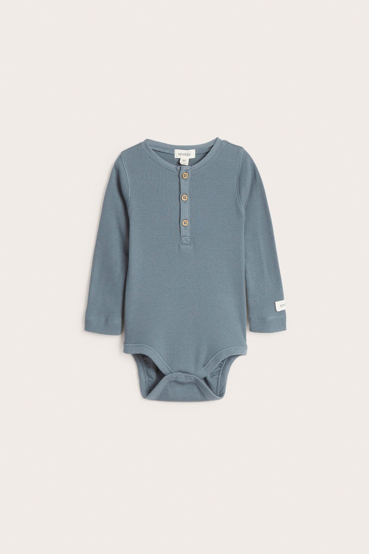 Front view of a baby's blue ribbed long-sleeved bodysuit with a button placket and snap buttons.