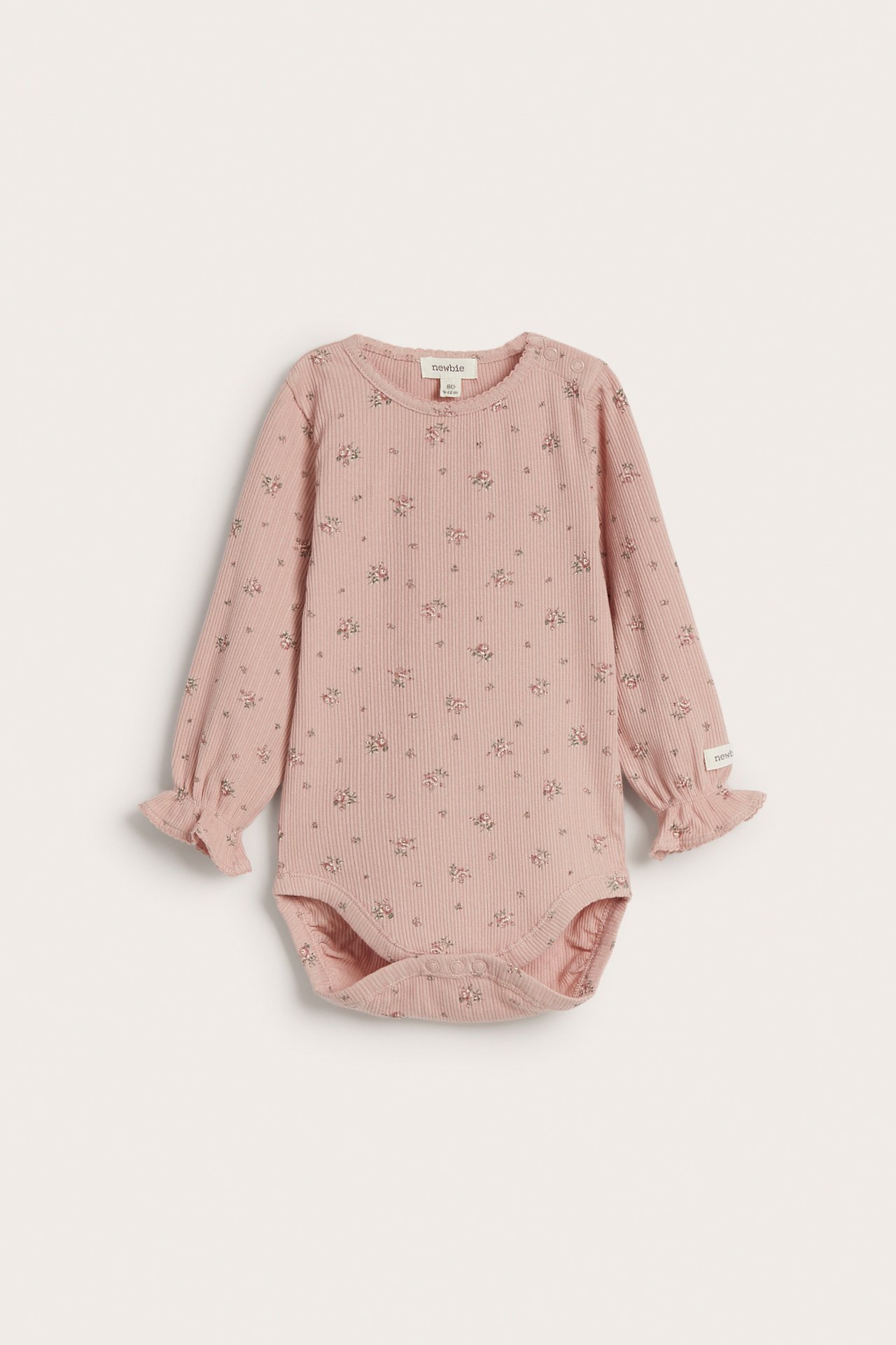 Vorderansicht eines pinkfarbenen gerippten Babybodys mit Blumenmuster, langen Rüschenärmeln und Druckknöpfen.