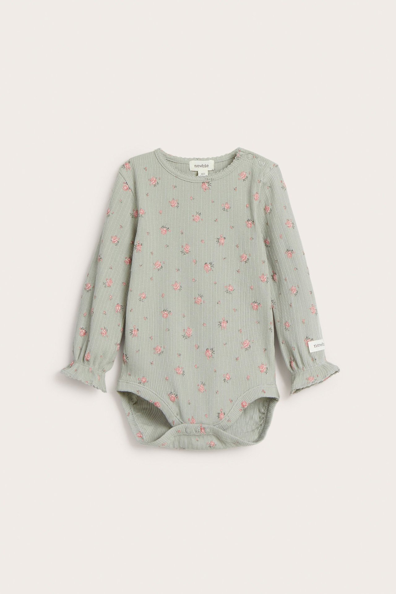 Vorderansicht: Baby-Body aus grünem Rippstrick mit Blumenmuster, langen Rüschenärmeln und Picot-Besatz.