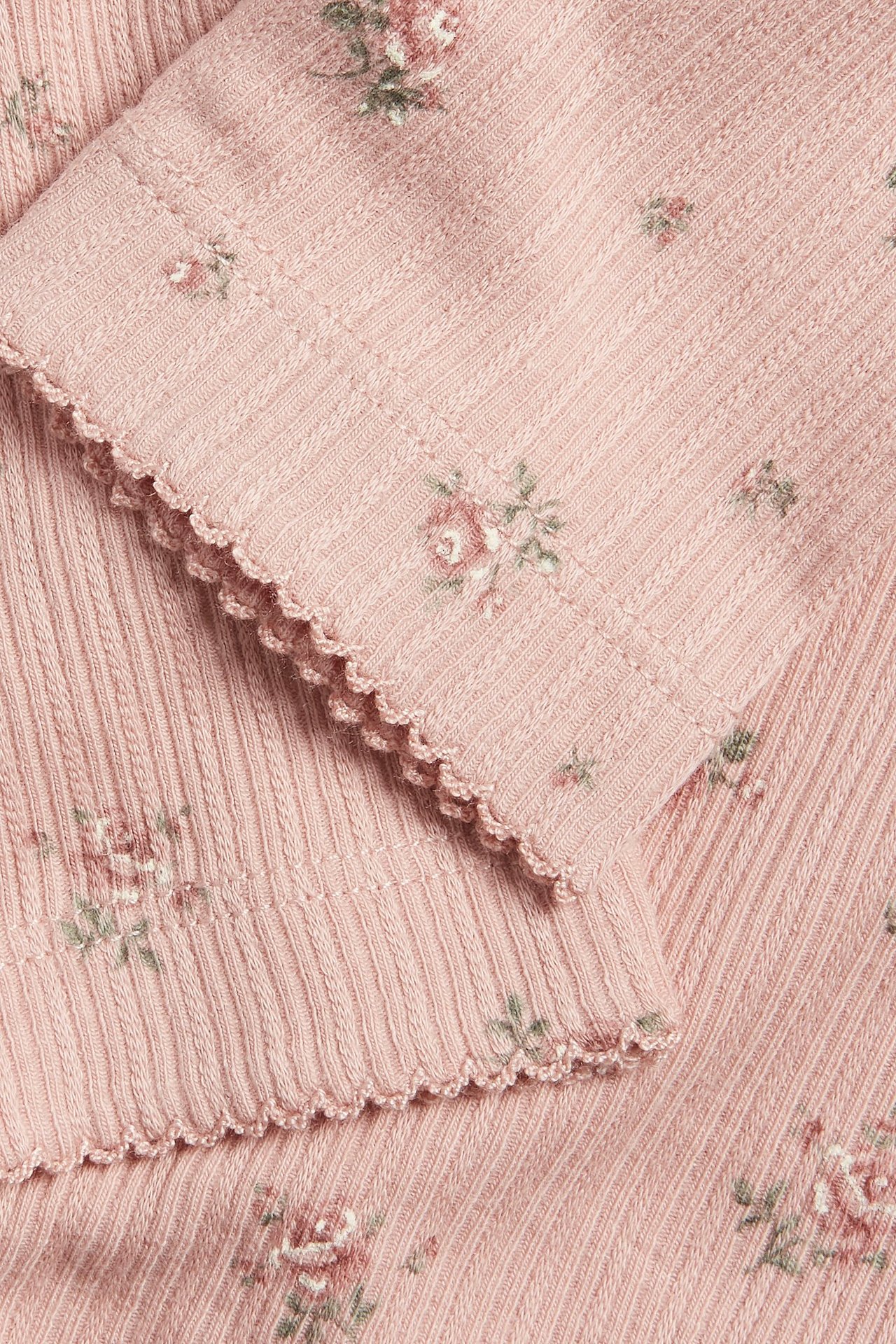 Nahaufnahme von rosa gerippten Leggings mit Blumenmuster und Picot-Saum.