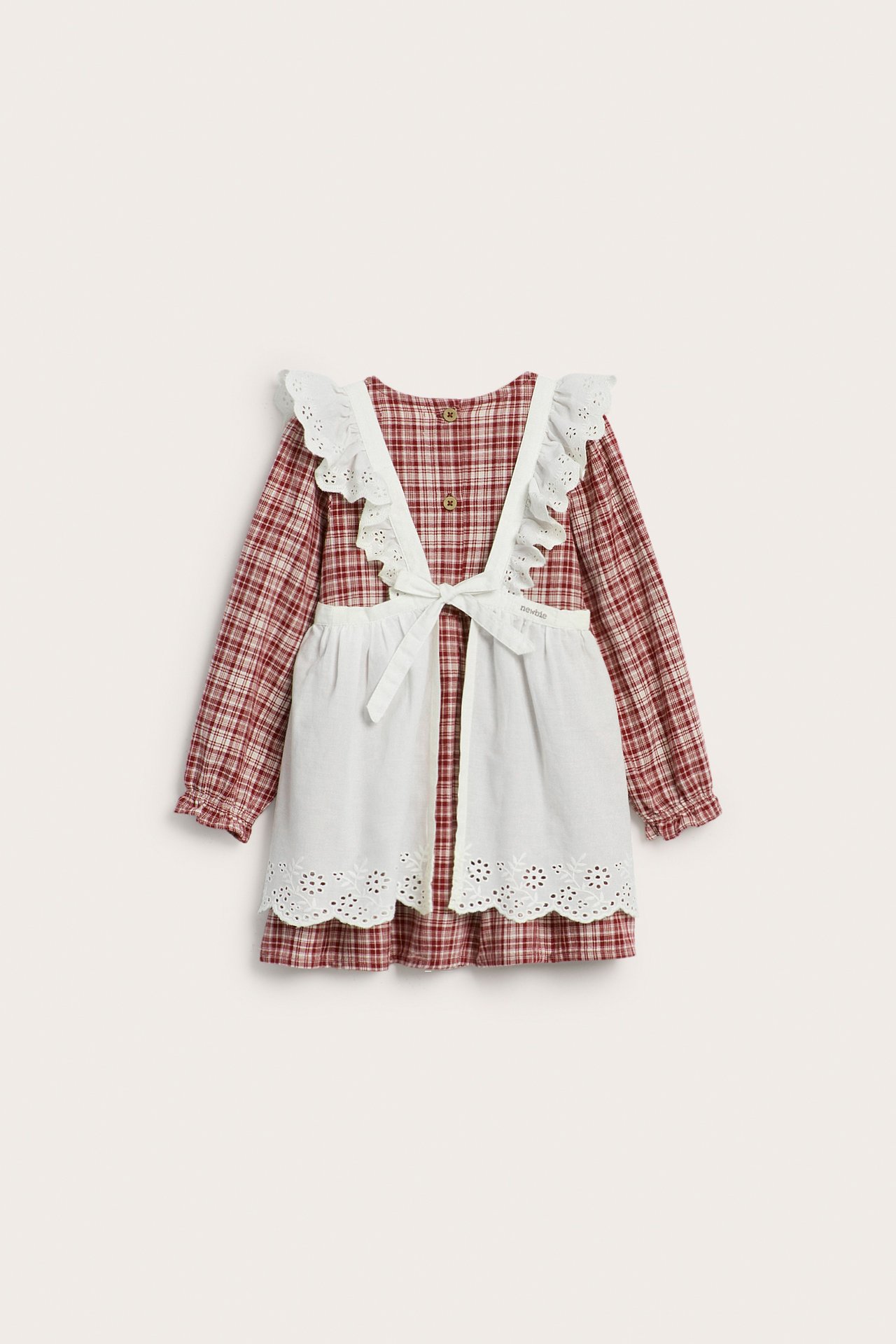 Vorderansicht: Rot kariertes Kinder-Baumwollkleid mit weißer bestickter Schürze darüber gebunden.